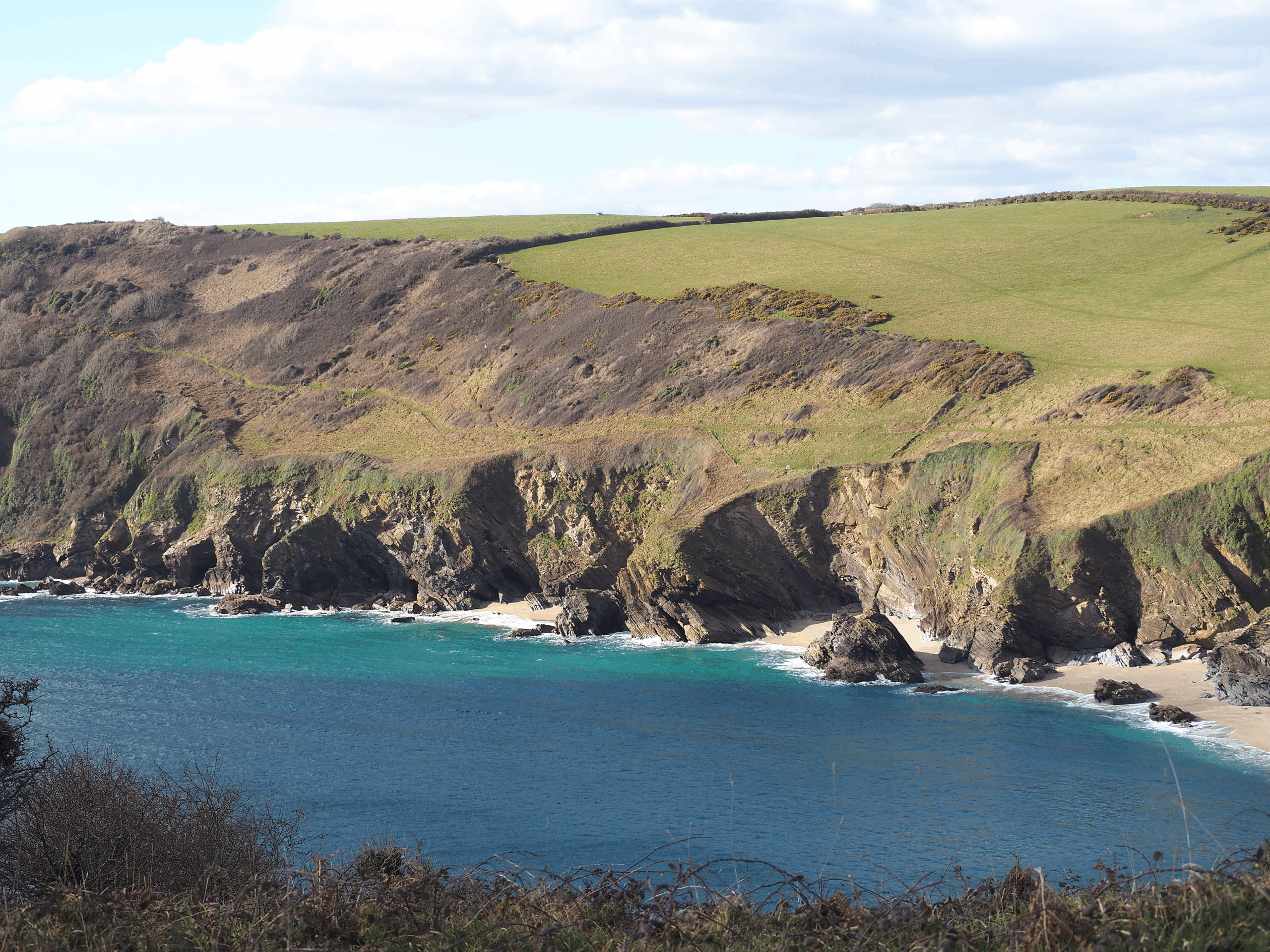 Small bays are nestled below rocky and tufted cliffs. Pale sandy beaches sit below and meet the turquoise sea. Winter colours of bracken and heather meet green pastures above.
